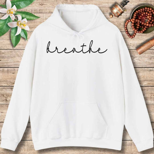 White hoodie with 'breathe' text on a wooden surface with flowers and beads.